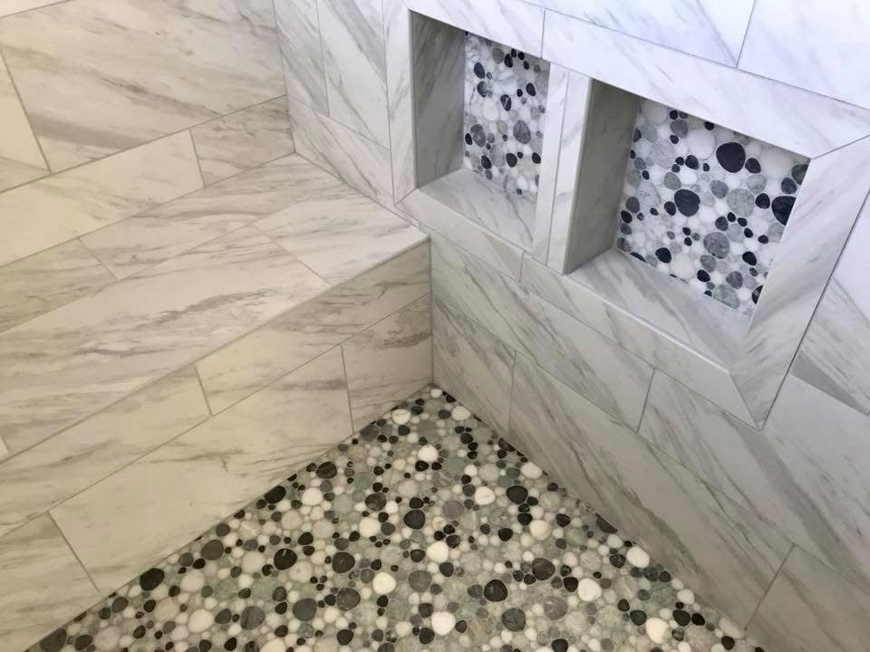 Marble tile shower with a pebble floor